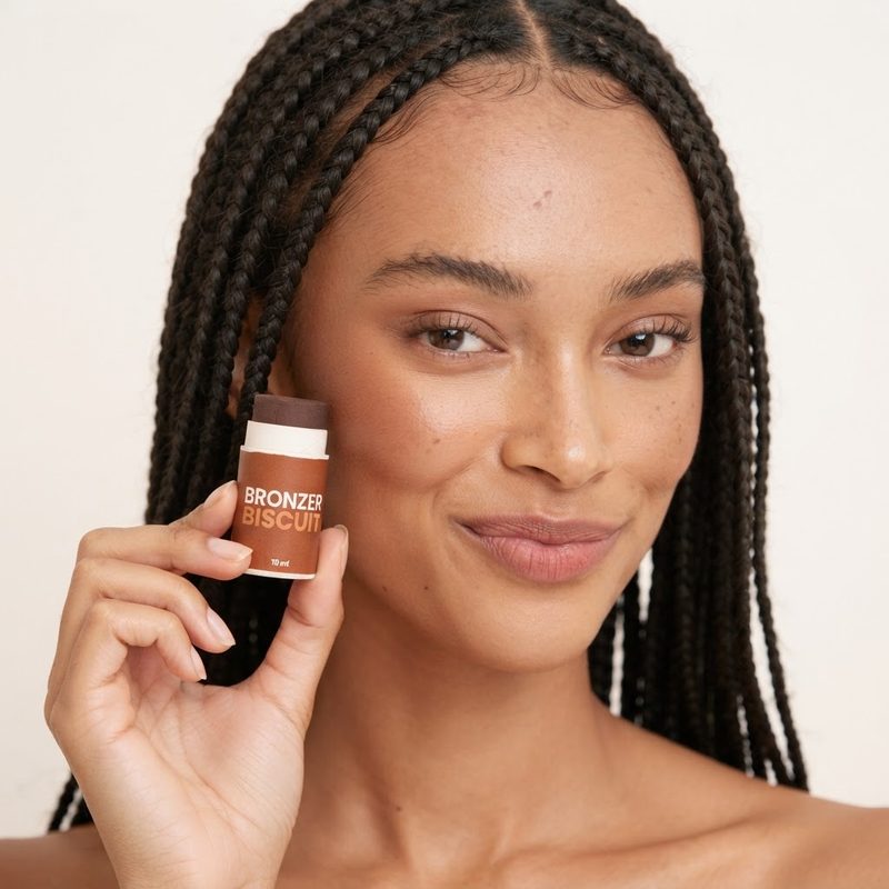 Modella dalla pelle medio-scura con in mano il bronzer in stick Biscuit di Enooso