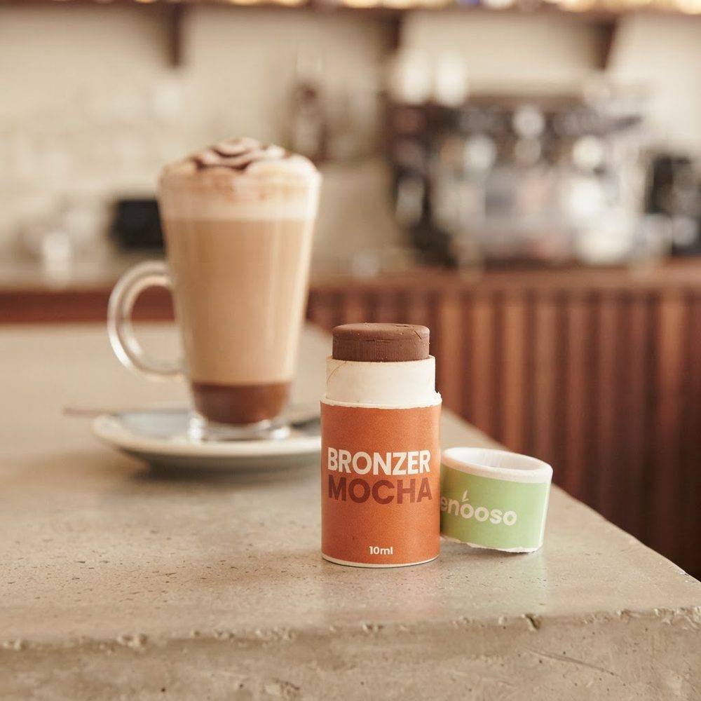 Il bronzer in stick Mocha sul bancone di un bar con un latte macchiato